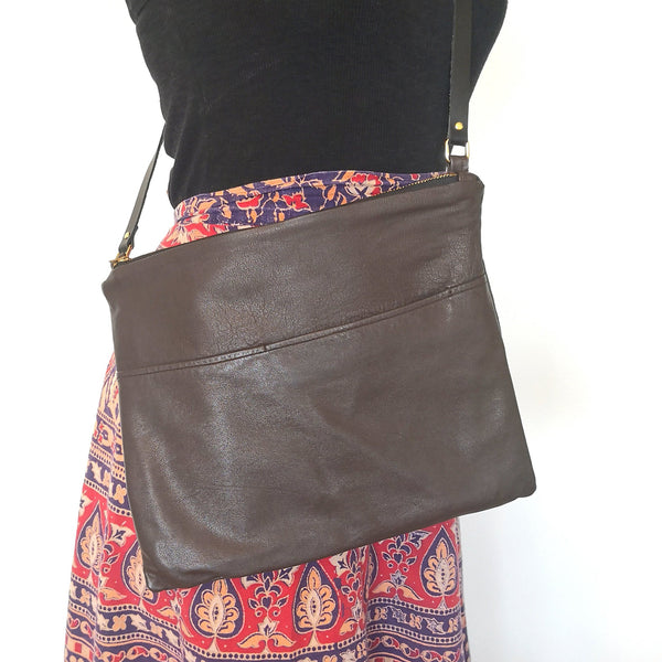 Woman wearing upcycled brown leather crossbody bag in a classic silhouette