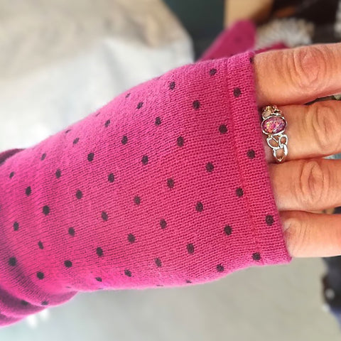Hand wearing long fingerless Kitten Mittens in pink with black dots