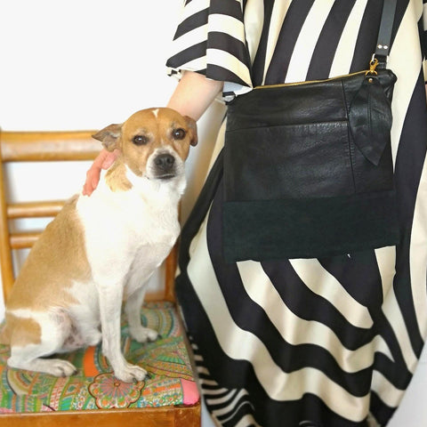 Woman in striped dress and Fringe Vintage recycled black leather bag stands next to her dog