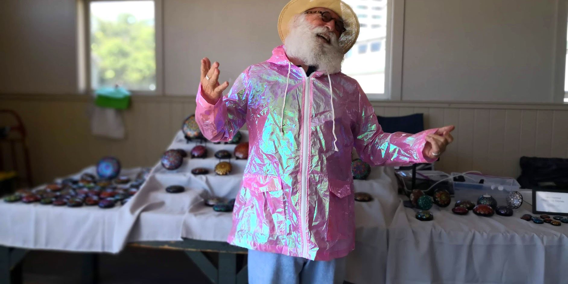 White-bearded man laughs modeling holographic raincoat