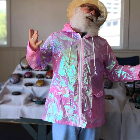 White-bearded man laughs modeling holographic raincoat