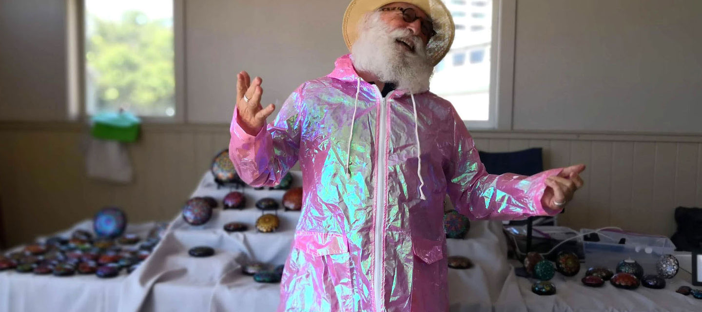 Older man with white beard laughing and wearing pink holographic raincoat