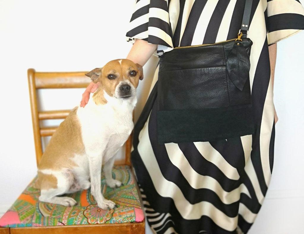 Woman wearing recycled black leather Fringe Vintage bag stands next to her dog